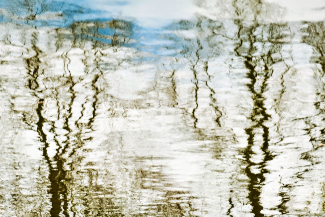 Abstract photograph of a reflection with wavy patterns in white, blue, and brown tones.
