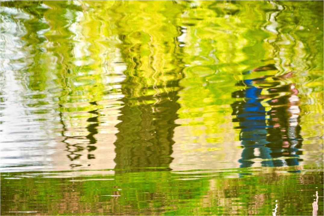 Reflection of people in a body of water with green and yellow hues.